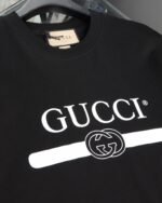 Gucci（グッチ） コピー 芸能人 ベルトロゴダブルgテーププリントラウンドネック半袖Tシャツ